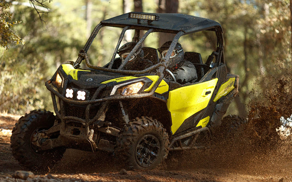 UTV amarelo espirrando lama em trilha de terra no meio da mata